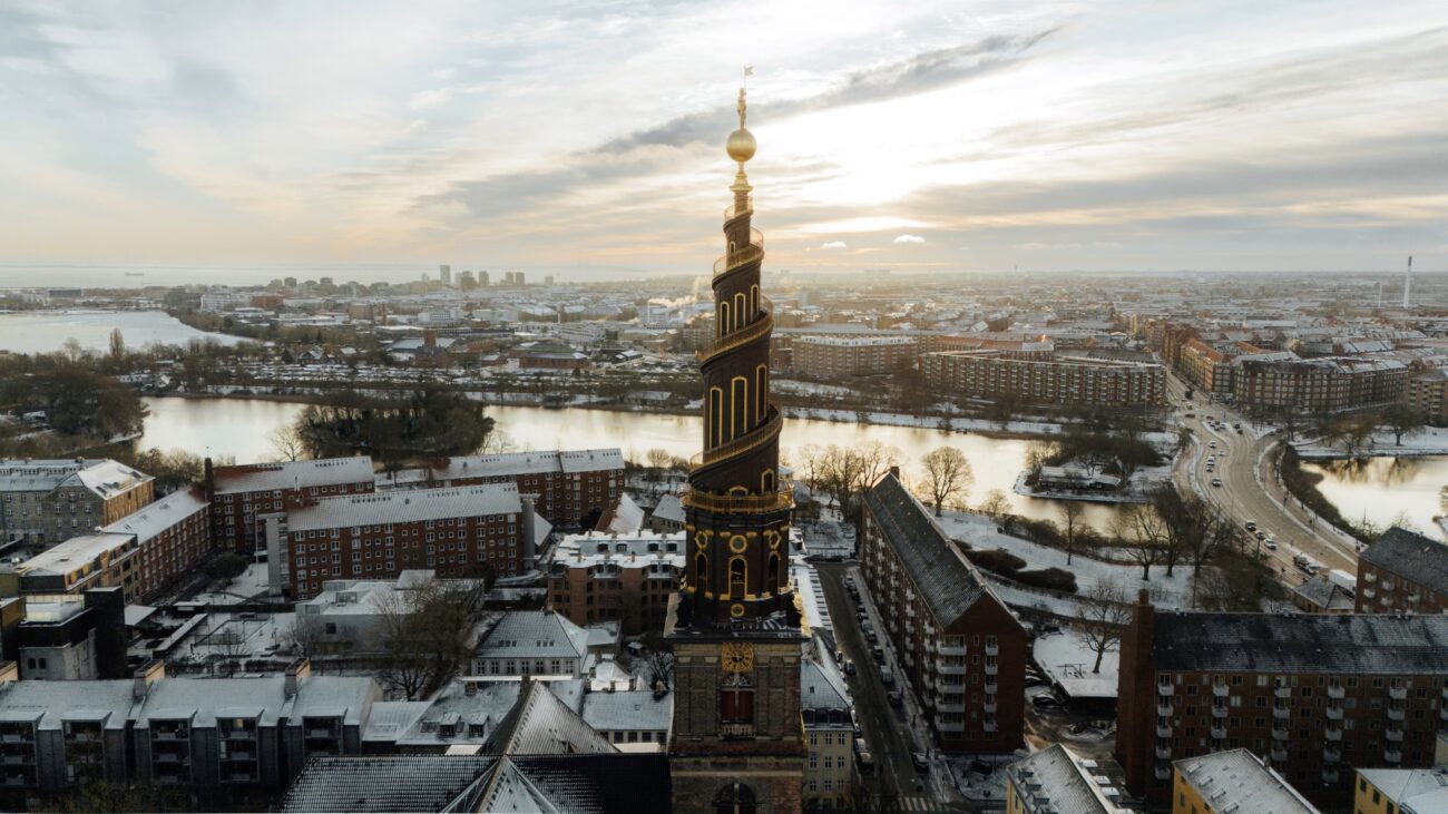 Der gold verzierte Turm der Erlöserkirche vor den verschneiten Dächern Kopenhagens