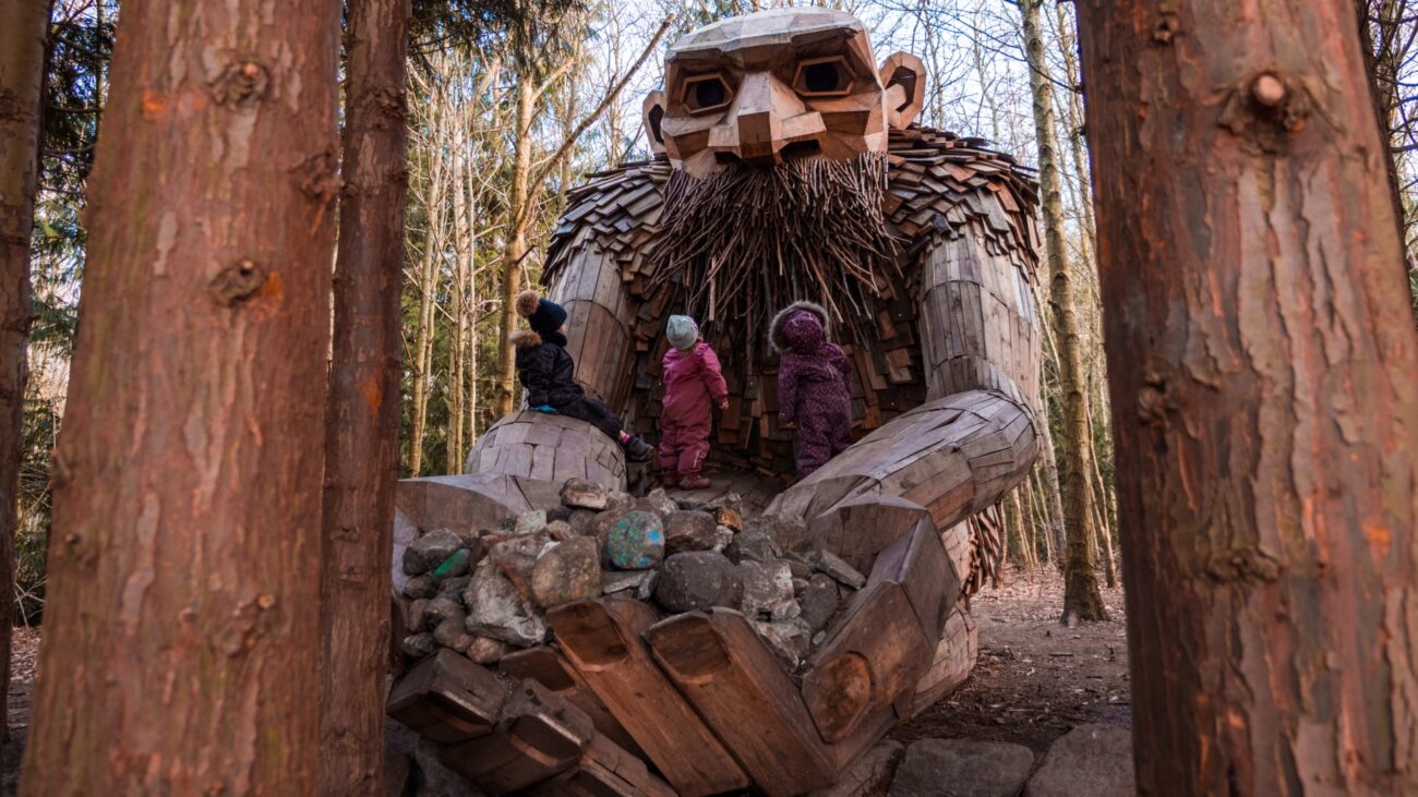 A large wooden figure holding both hands up with children standing on them