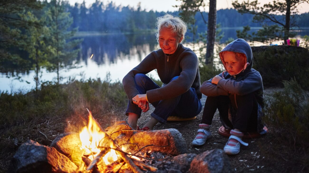 Zwei Kinder sitzen am Lagerfeuer